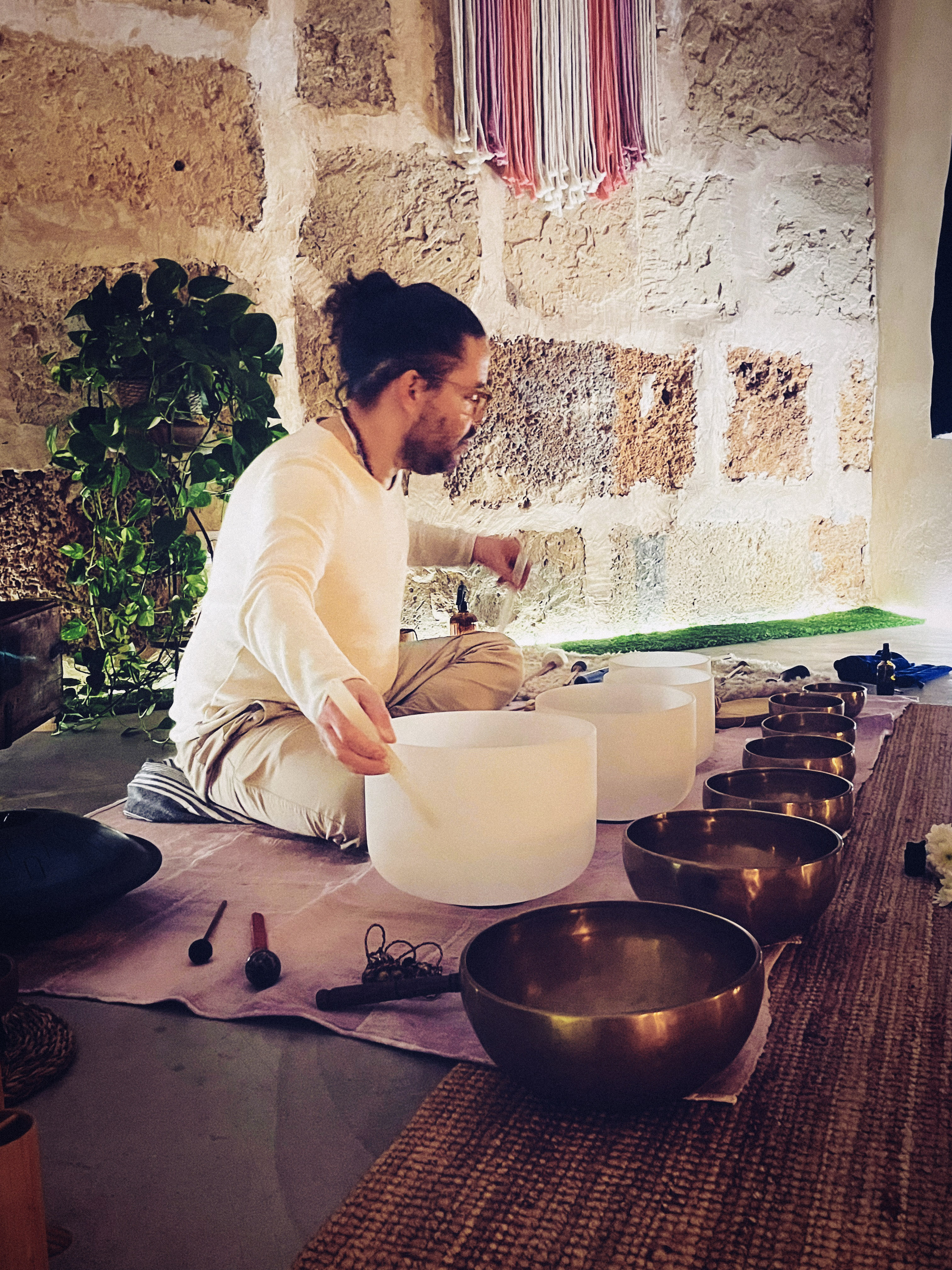 Diego playing crystal bowls in a stone-walled room.