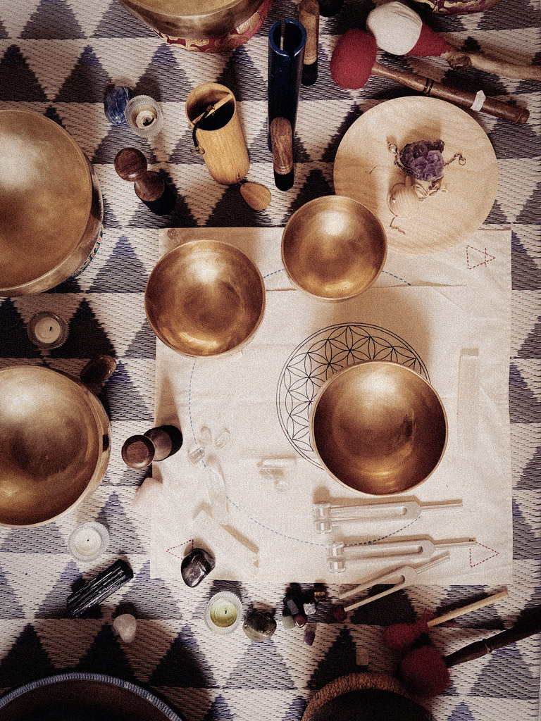 Metal bowls and sound instruments arranged around a stitched geometric cloth.